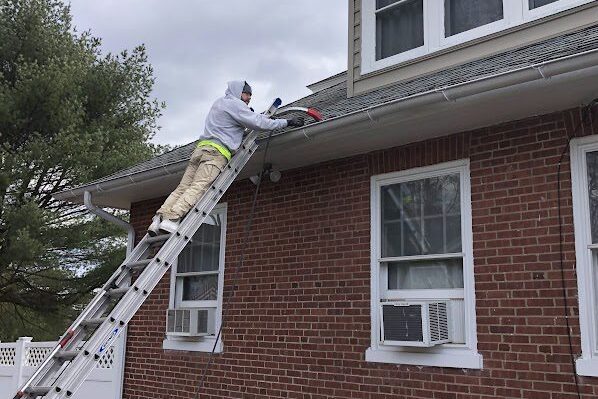 Gutter Cleanout - A technician performing a thorough gutter cleanout to prevent blockages and maintain proper drainage.